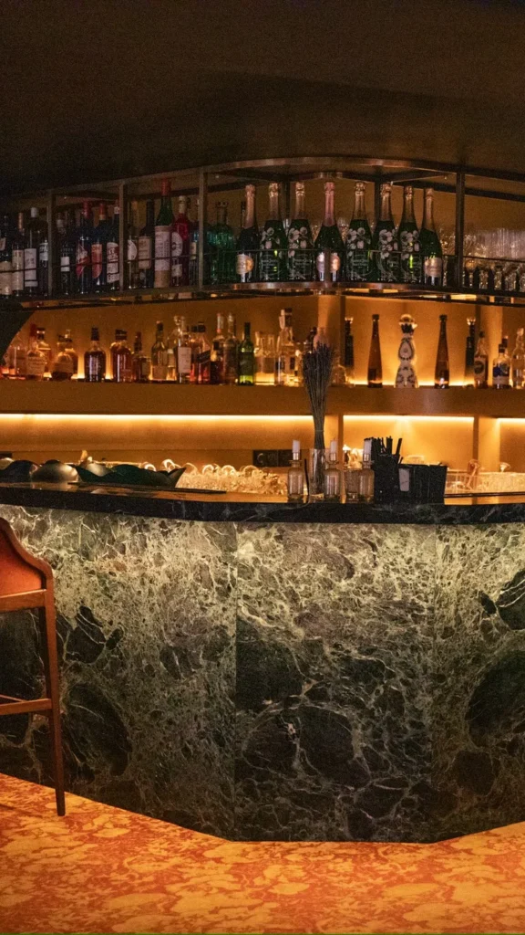 Warmly lit bar area with bottles and glassware at Siena Paris