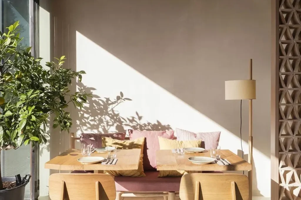 Sunlit corner banquette with striped cushions and a lemon tree beside a set table at SPOT Palma De Mallorca