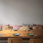 Pine table set with green plates before a banquette of striped and linen cushions at SPOT Palma De Mallorca