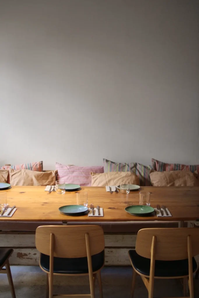 Pine table set with green plates before a banquette of striped and linen cushions at SPOT Palma De Mallorca