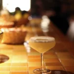 Foam-topped cocktail with a dried citrus wheel on a tiled counter at SPOT Palma De Mallorca