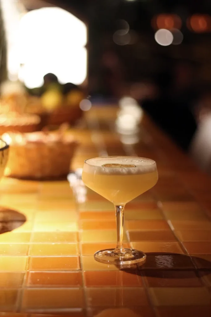 Foam-topped cocktail with a dried citrus wheel on a tiled counter at SPOT Palma De Mallorca