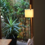 Planted courtyard with a trellis wall and floor lamp seen past a cushioned bench at SPOT Palma De Mallorca