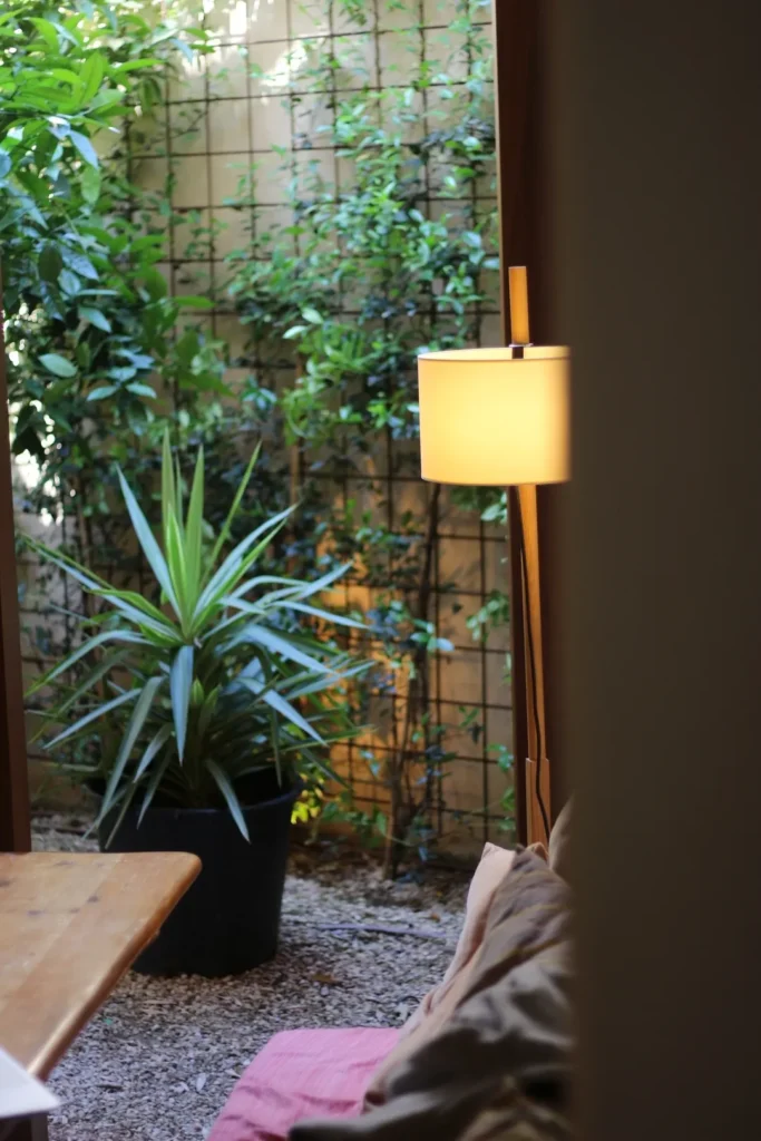 Planted courtyard with a trellis wall and floor lamp seen past a cushioned bench at SPOT Palma De Mallorca