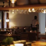 Candlelit dining room with a waiter crossing between banquettes at dusk at SPOT Palma De Mallorca