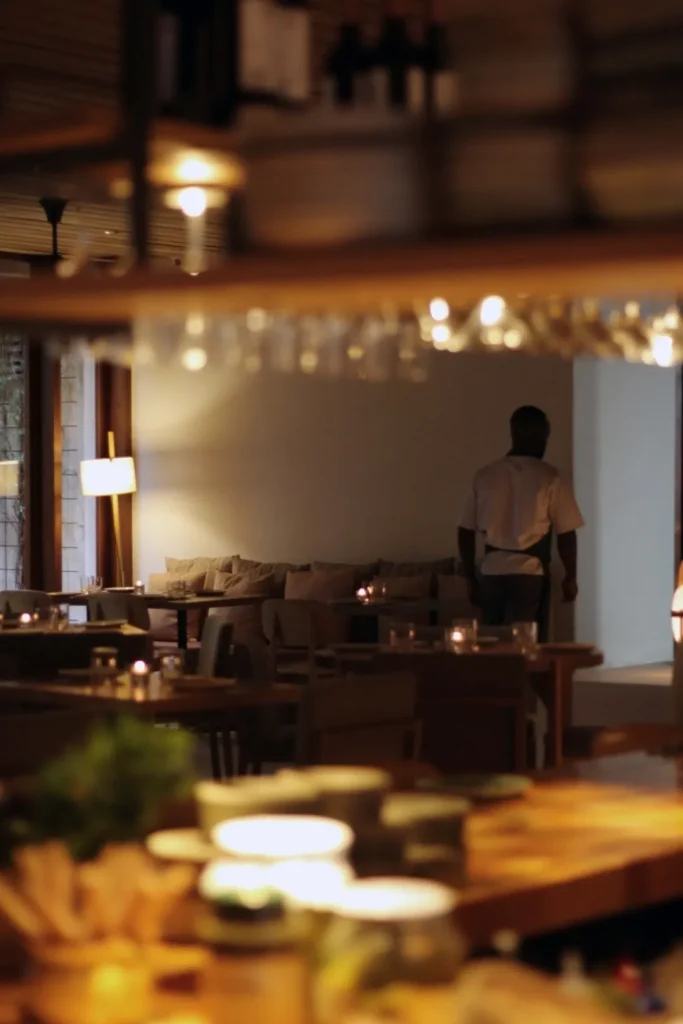 Candlelit dining room with a waiter crossing between banquettes at dusk at SPOT Palma De Mallorca