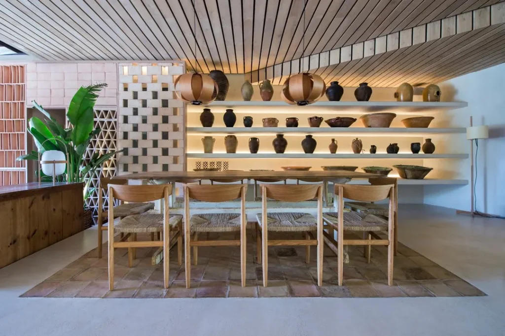 Long communal table beneath a slatted ceiling and shelves of earthenware pots at SPOT Palma De Mallorca