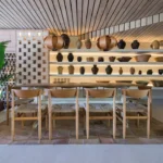 Long communal table beneath a slatted ceiling and shelves of earthenware pots at SPOT Palma De Mallorca