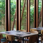 Set tables beside angled wood-framed windows looking onto greenery at SPOT Palma De Mallorca