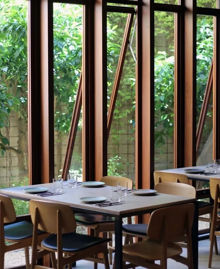 Set tables beside angled wood-framed windows looking onto greenery at SPOT Palma De Mallorca