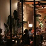 Guests dining at night seen past plants and a brick screen at SPOT Palma De Mallorca