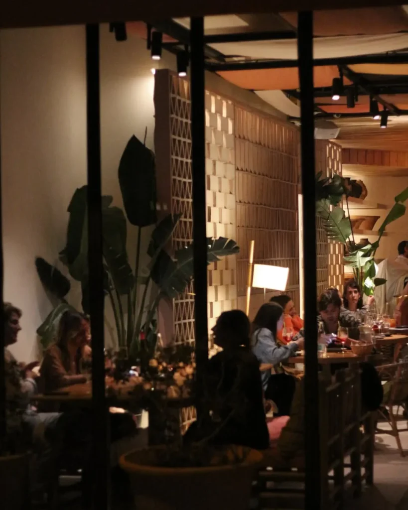 Guests dining at night seen past plants and a brick screen at SPOT Palma De Mallorca