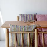 Wooden table and log chairs dressed with rainbow-striped cushions at SPOT Palma De Mallorca