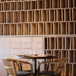 Round table and rattan chairs against a backlit stacked-brick lattice wall at SPOT Palma De Mallorca