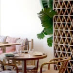 Round table with rattan armchairs beside a breeze-block screen and banana plant at SPOT Palma De Mallorca