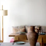 Table with a terracotta jug and green plates before a striped-cushion banquette at SPOT Palma De Mallorca