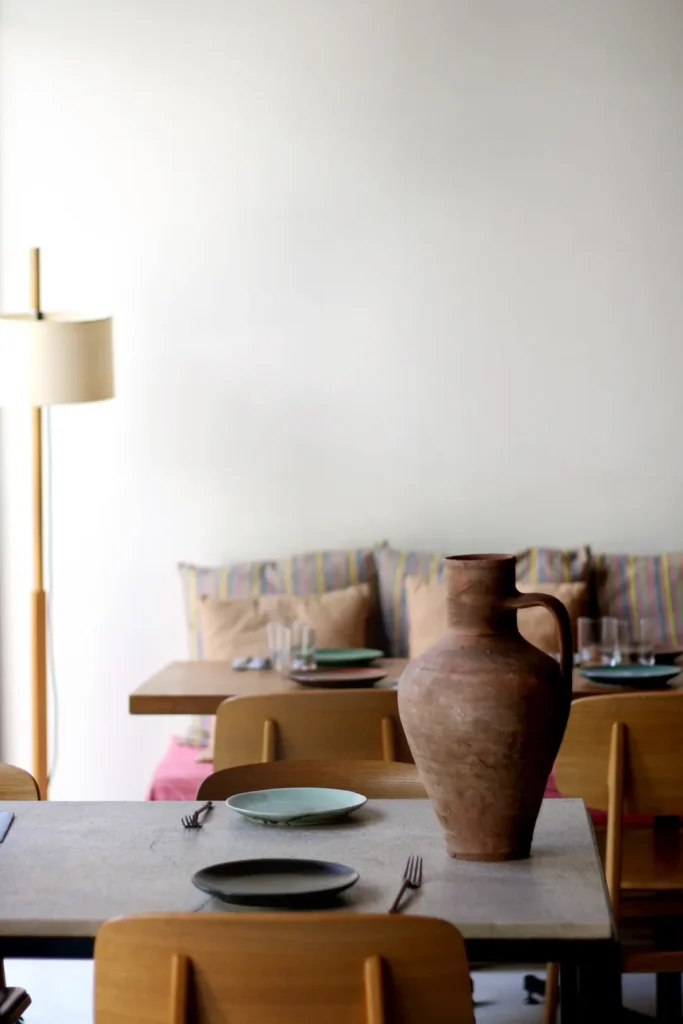 Table with a terracotta jug and green plates before a striped-cushion banquette at SPOT Palma De Mallorca