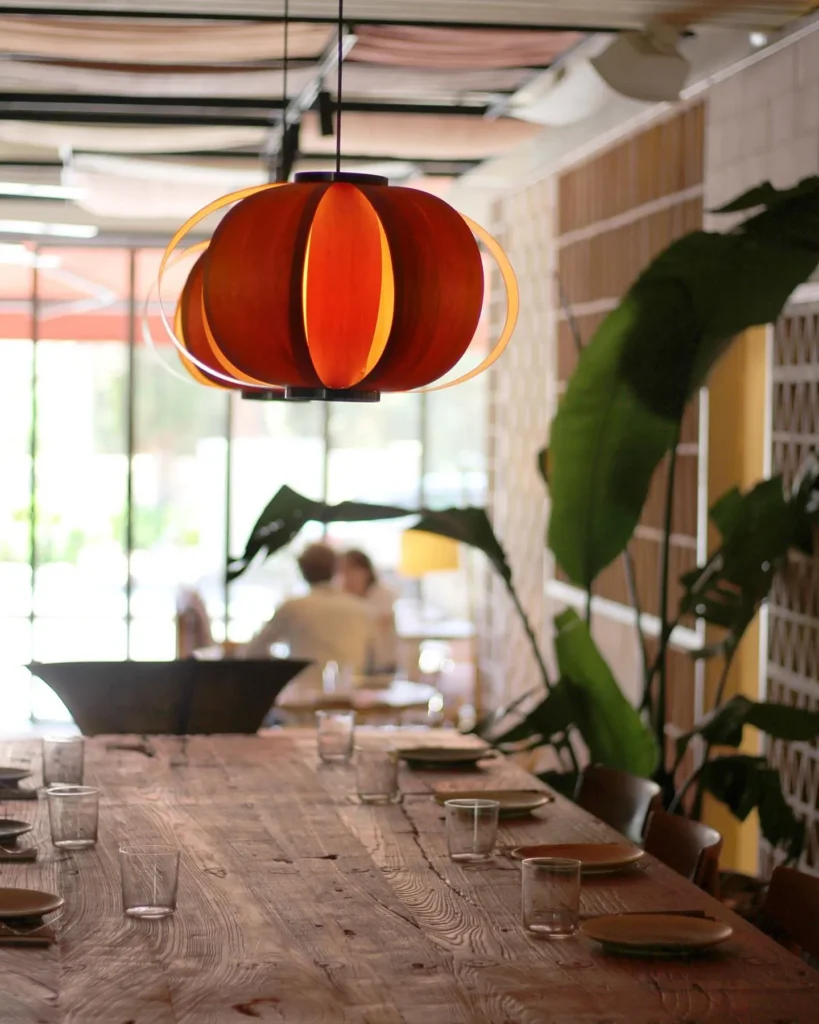 Orange melon pendant lamp over a wood table by the garden windows at SPOT Palma De Mallorca