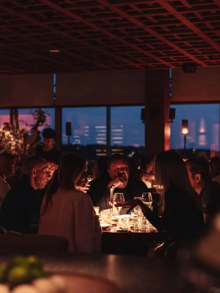 Guests dining by candlelight with city lights through the windows at Zuma Cannes