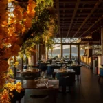 Dining room bathed in sunset light with floral displays and a sea view at Zuma Cannes