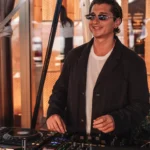 DJ in sunglasses mixing at the decks in golden light at Zuma Cannes