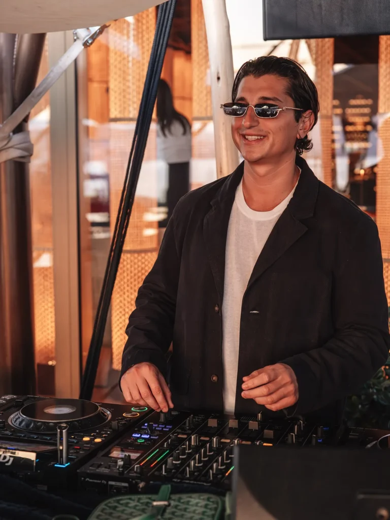 DJ in sunglasses mixing at the decks in golden light at Zuma Cannes