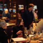 Guest seated at a candlelit table in the busy dining room at Zuma Cannes