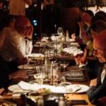 Guests seated along a long table over dinner and drinks at Zuma Cannes