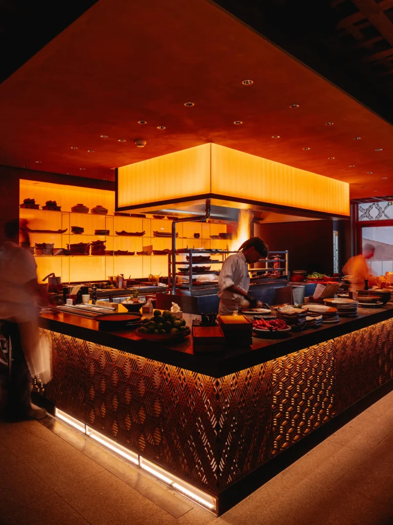 Chef cooking over the open flame of the robata grill in the show kitchen at Zuma Cannes