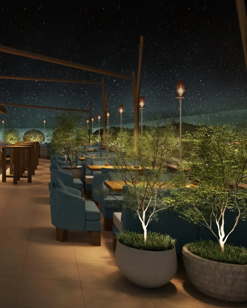 Rooftop terrace with blue armchairs, planted trees and torch lights under a starry sky at Zuma Cannes