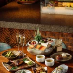 Spread of signature izakaya dishes and champagne on a table at Zuma Cannes