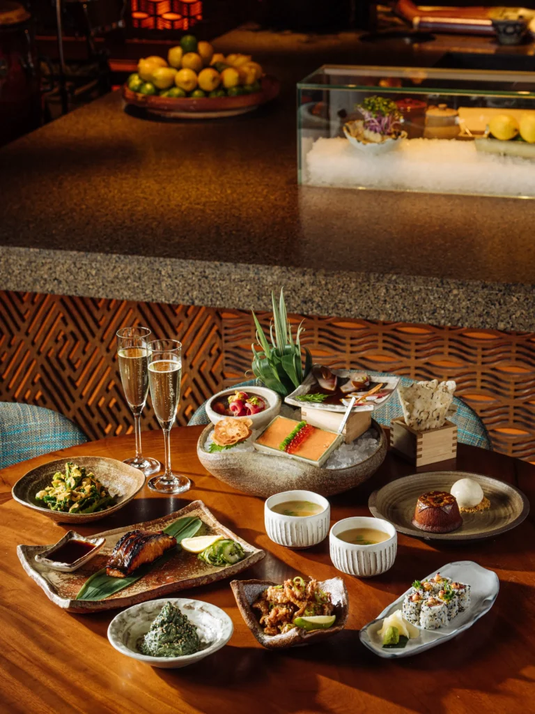 Spread of signature izakaya dishes and champagne on a table at Zuma Cannes