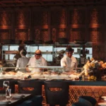 Chefs in headbands working the sushi counter beneath latticed wood panelling at Zuma Cannes