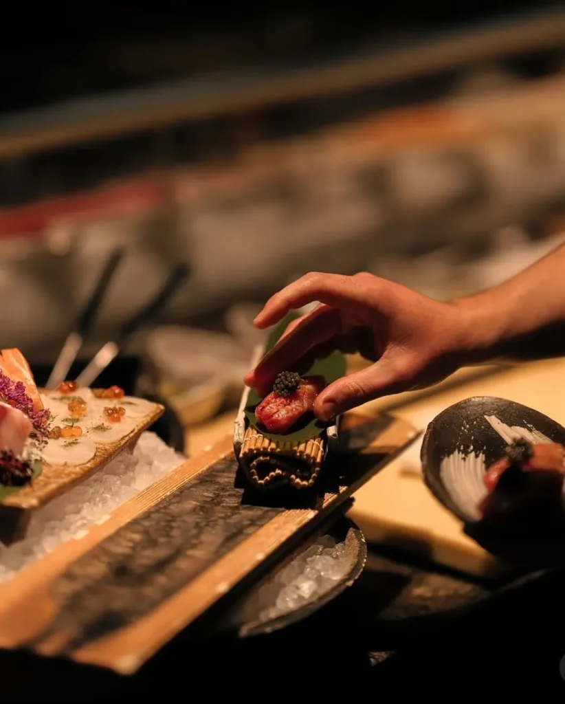 Chef plating caviar-topped nigiri at the sushi counter at Zuma Cannes