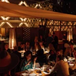 Guests dining under warm lighting and patio heaters on the evening terrace at Zuma Cannes