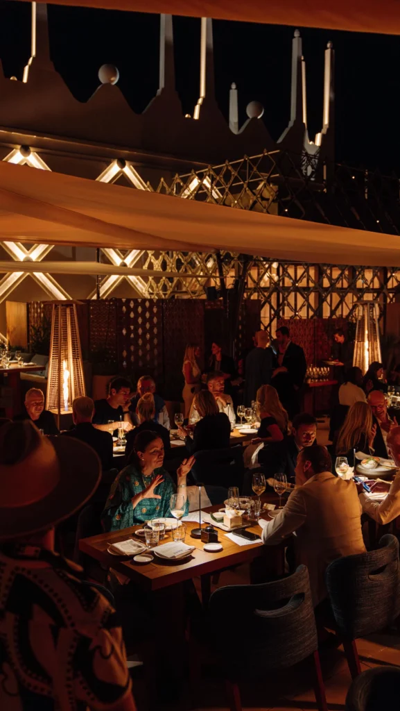 Guests dining under warm lighting and patio heaters on the evening terrace at Zuma Cannes