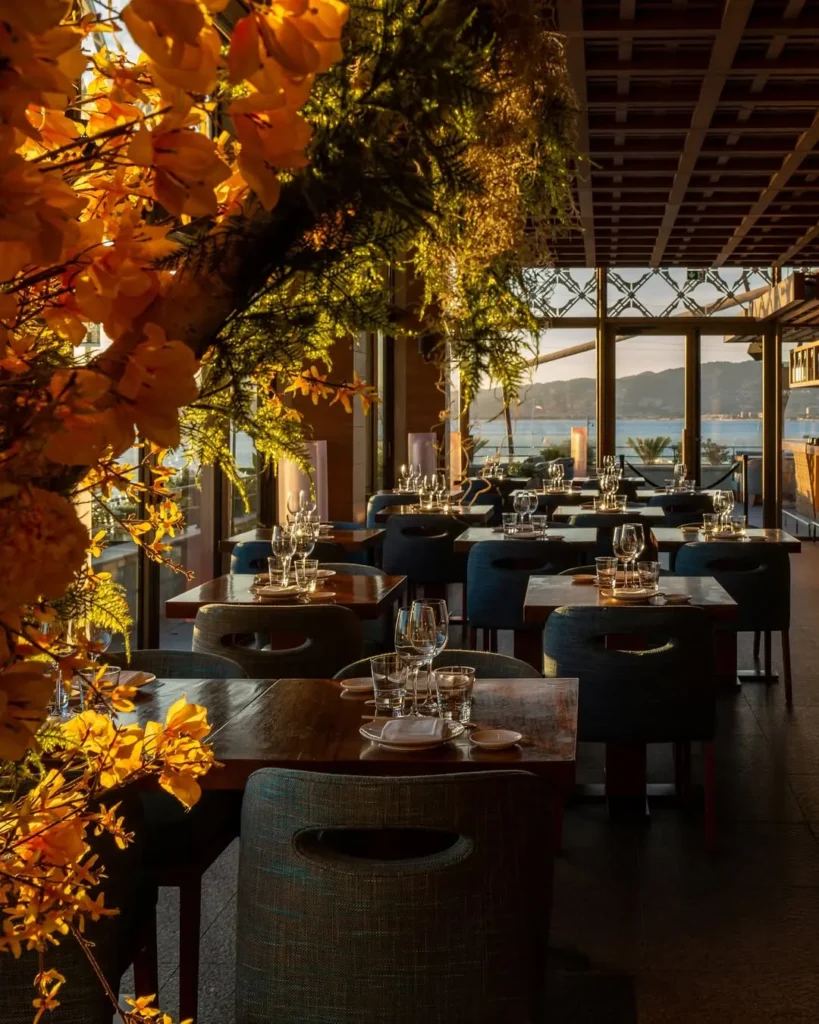 Terrace tables framed by flowers with a sea view at Zuma Cannes