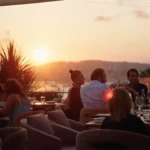 Guests on the terrace at sunset with the sun setting over the bay at Zuma Cannes