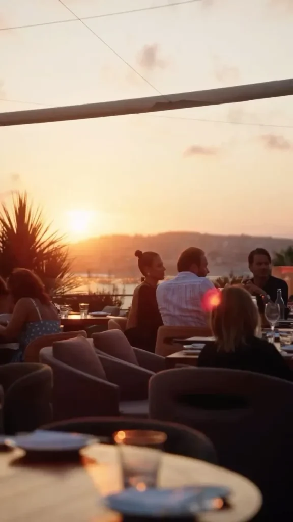 Guests on the terrace at sunset with the sun setting over the bay at Zuma Cannes