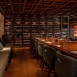 Private dining table beside a floor-to-ceiling wine wall at Zuma Cannes