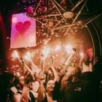 Crowd celebrating under colorful lights at Boum Boum Paris