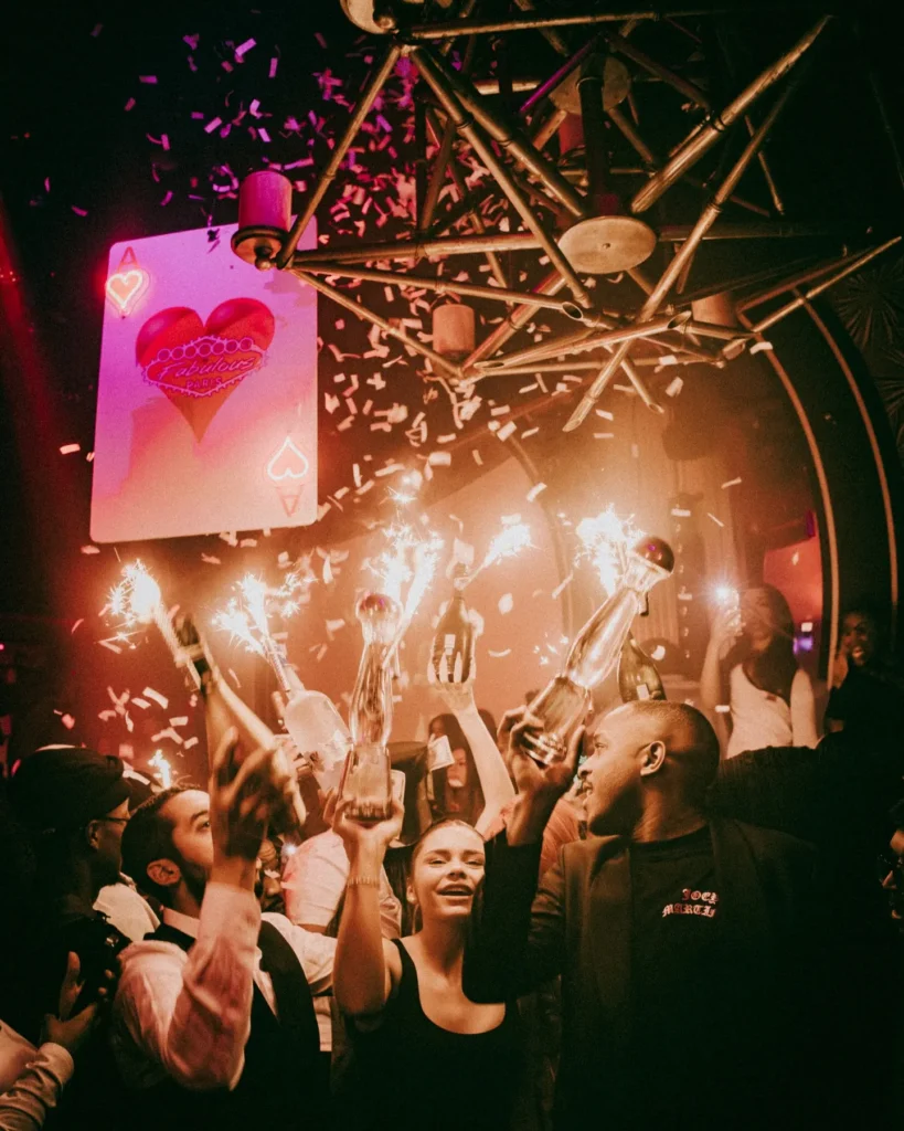 Crowd celebrating under colorful lights at Boum Boum Paris