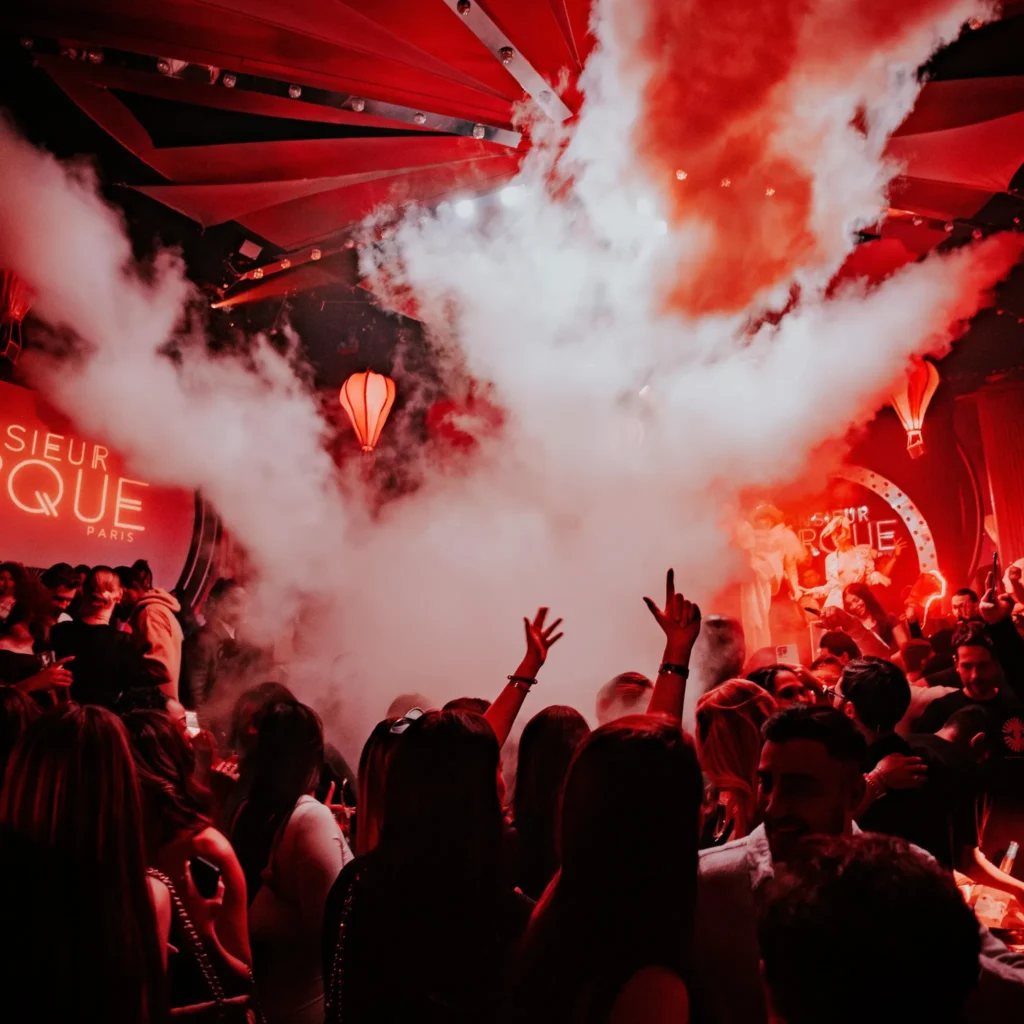 Crowd celebrating beneath red lights at Boum Boum Paris