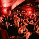 Guests dancing under red lights at Deflower Paris