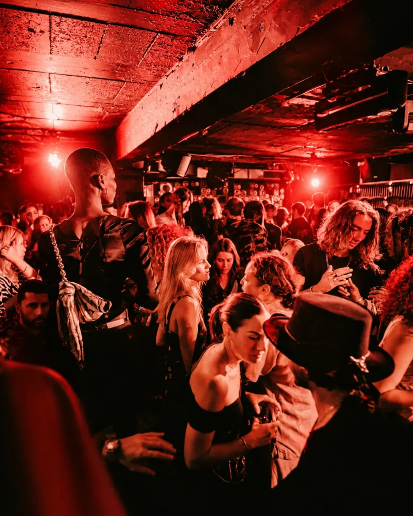 Guests dancing under red lights at Deflower Paris