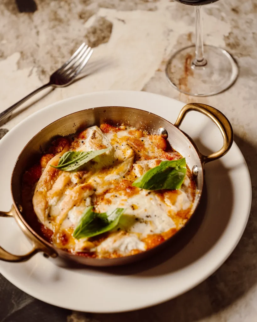 Baked Italian dish topped with cheese and herbs at Giulia Ristorante Paris