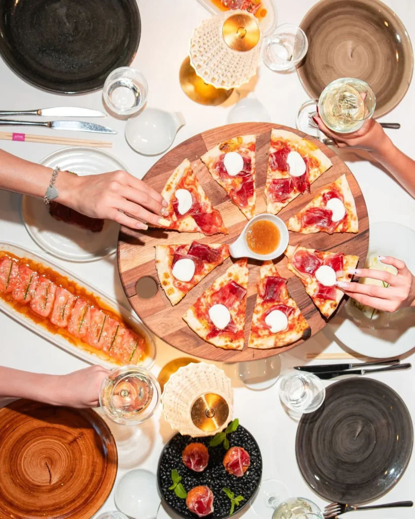 Pizza and drinks arranged on a table at JustMe Milano