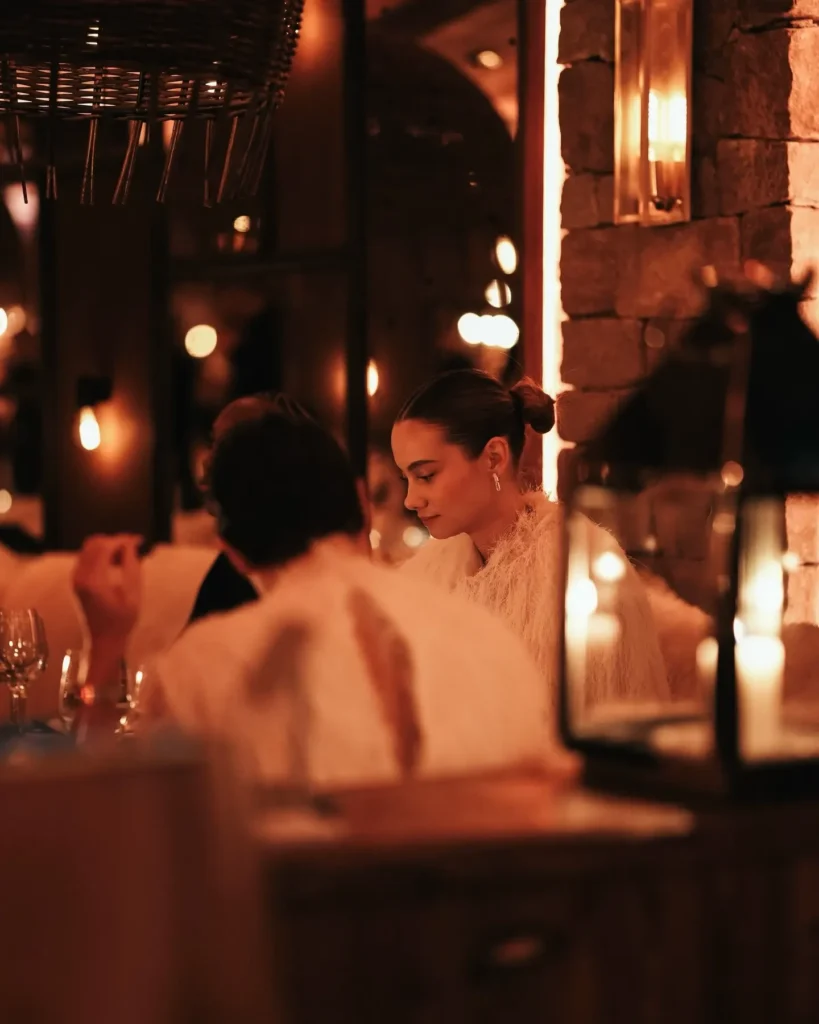 Guests dining in the warm candlelit interior of La Ferme Saint-Amour Courchevel