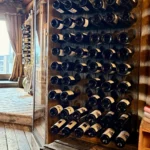 Wine bottles displayed in the wooden cellar at La Soucoupe Courchevel