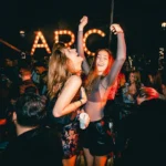 Guests dancing beneath the L'Arc Paris illuminated sign